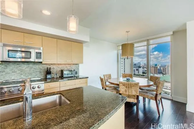 a kitchen with stainless steel appliances granite countertop a stove top oven a sink dishwasher a dining table and chairs with wooden floor