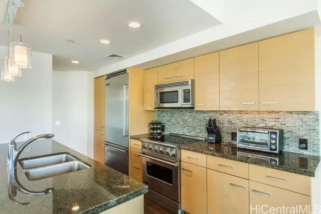 a kitchen with stainless steel appliances granite countertop a stove a sink and a microwave