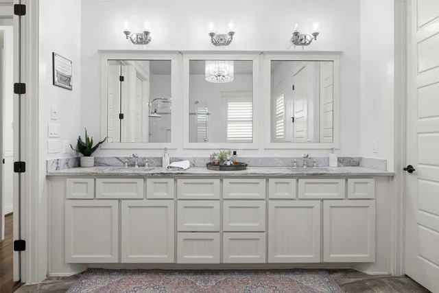 a large spacious bathroom with a granite countertop double vanity sink a mirror and a bathtub