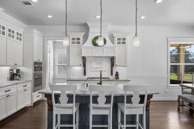 a kitchen with a dining table chairs cabinets and wooden floor