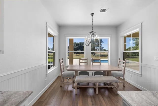 a dining room with furniture a chandelier and wooden floor
