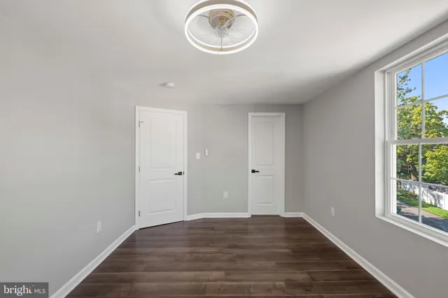 a view of an empty room with window and wooden floor