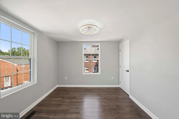 a view of an empty room with window and wooden floor