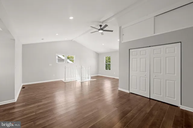 a kitchen with a stove a sink a refrigerator and white cabinets with wooden floor