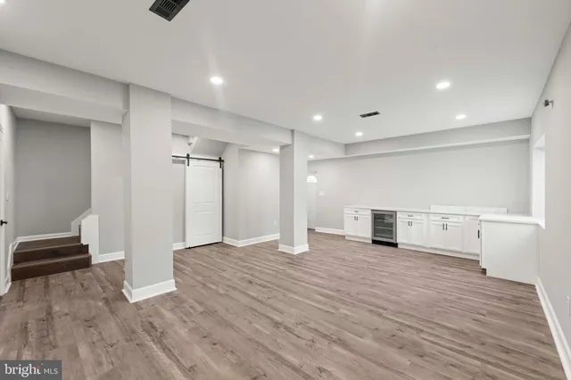 a view of a hallway with wooden floor and a bathroom