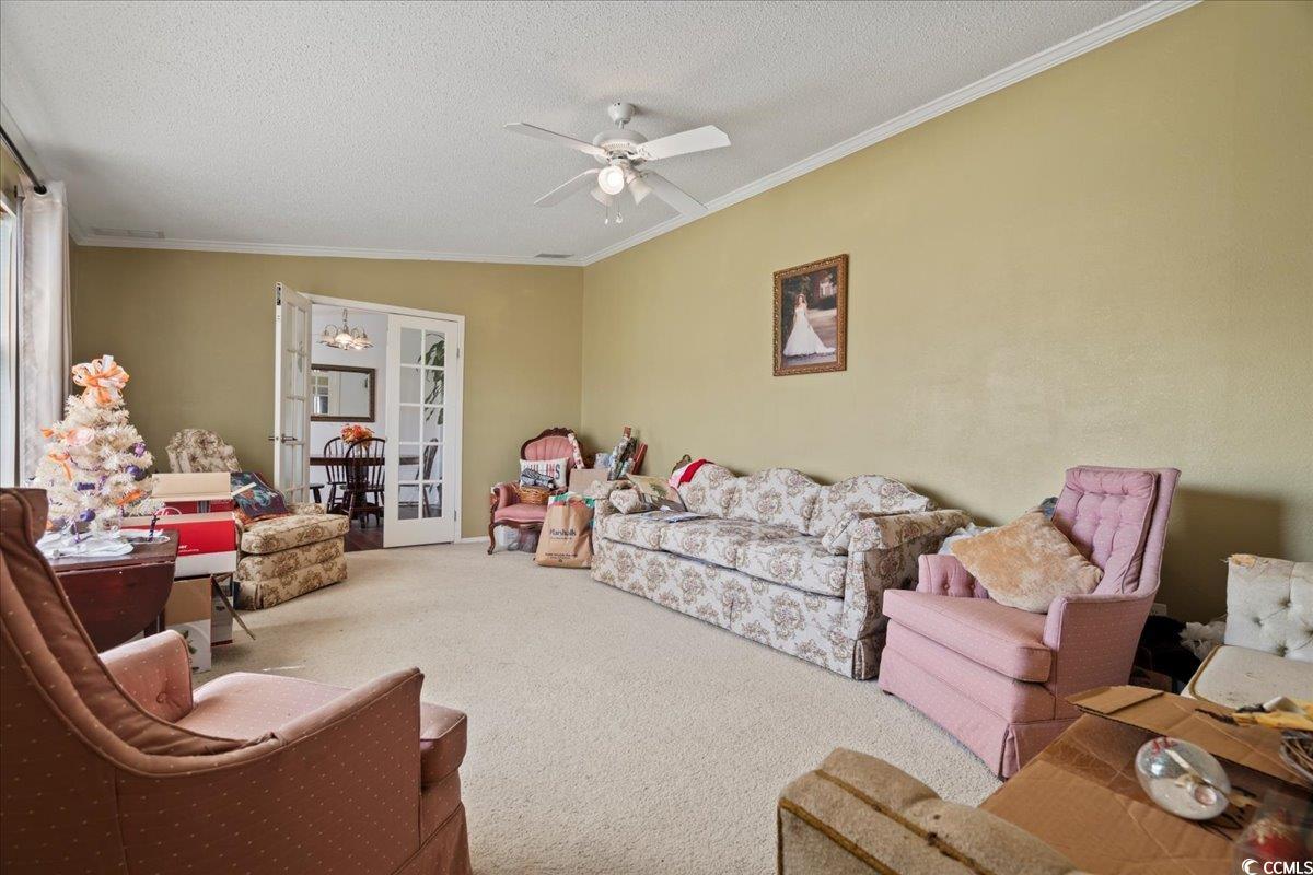 1130 Buck Swamp Road Fork, SC 29543 - Photo 3 of 35 Carpeted living area featuring a textured ceiling, ornamental molding, french doors, and ceiling fan with notable chandelier