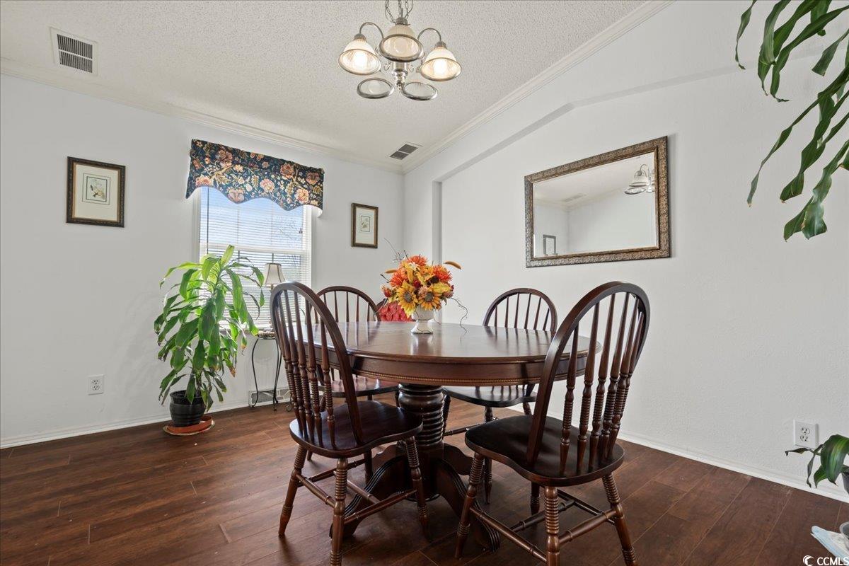 1130 Buck Swamp Road Fork, SC 29543 - Photo 6 of 35 Dining room featuring visible vents, hardwood / wood-style flooring, ornamental molding, and a chandelier