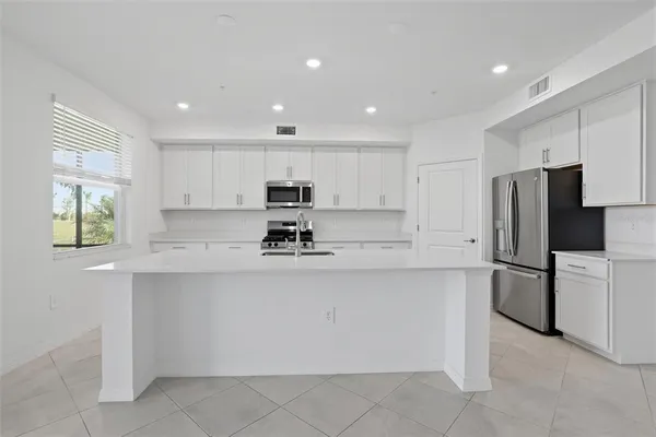 a kitchen with stainless steel appliances granite countertop white cabinets a refrigerator and a stove