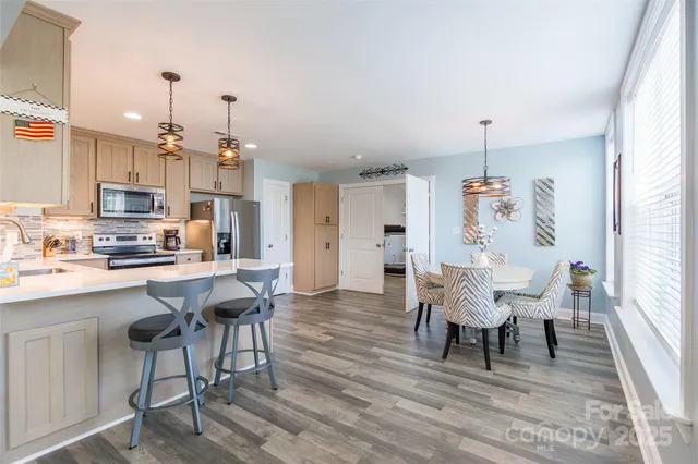 a kitchen with stainless steel appliances a dining table chairs refrigerator and cabinets