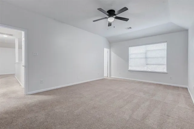 an empty room with windows and chandelier fan