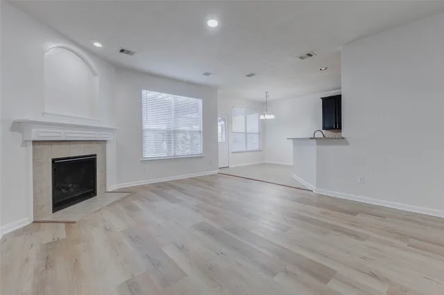 an empty room with wooden floor fireplace and windows