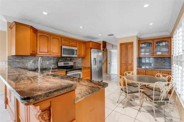 a kitchen with granite countertop a sink cabinets and stainless steel appliances