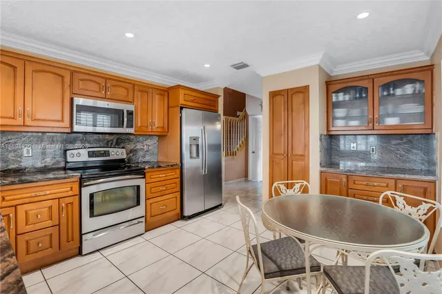 a kitchen with stainless steel appliances granite countertop a refrigerator and a stove top oven