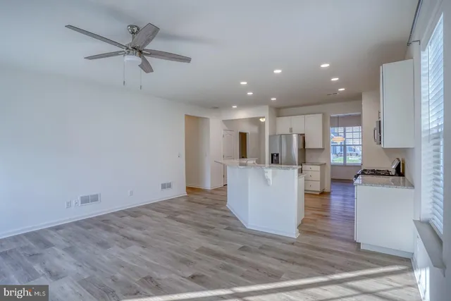 a view of a living room and kitchen with furniture appliances wooden floor and a window