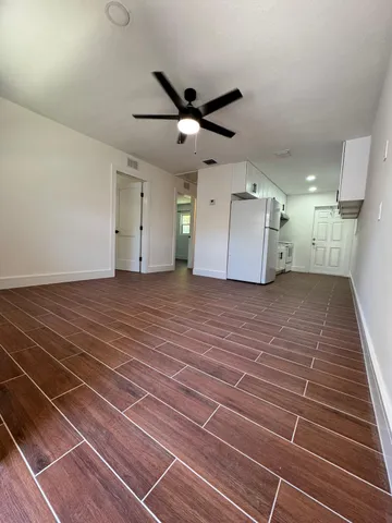 a view of a room with a ceiling fan and wooden floor