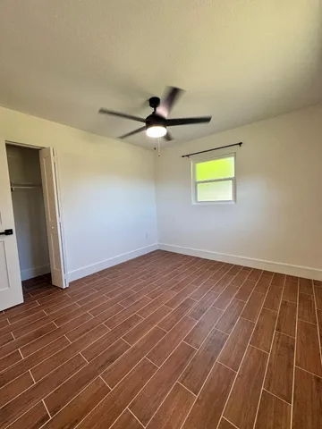 a view of an empty room with ceiling fan and window