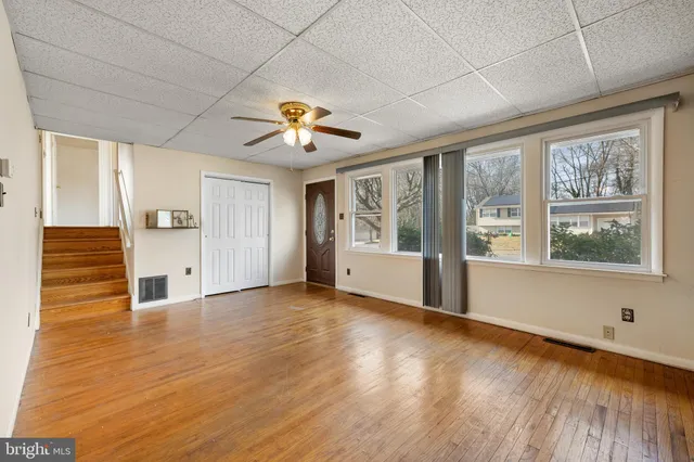 a view of a big room with wooden floor and a chandelier fan