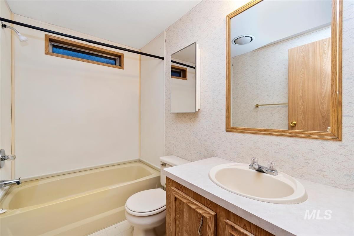 2804 Golden Rod Lane Caldwell, ID 83605 - Photo 11 of 35 Bathroom featuring tub / shower combination, vanity, and wallpapered walls