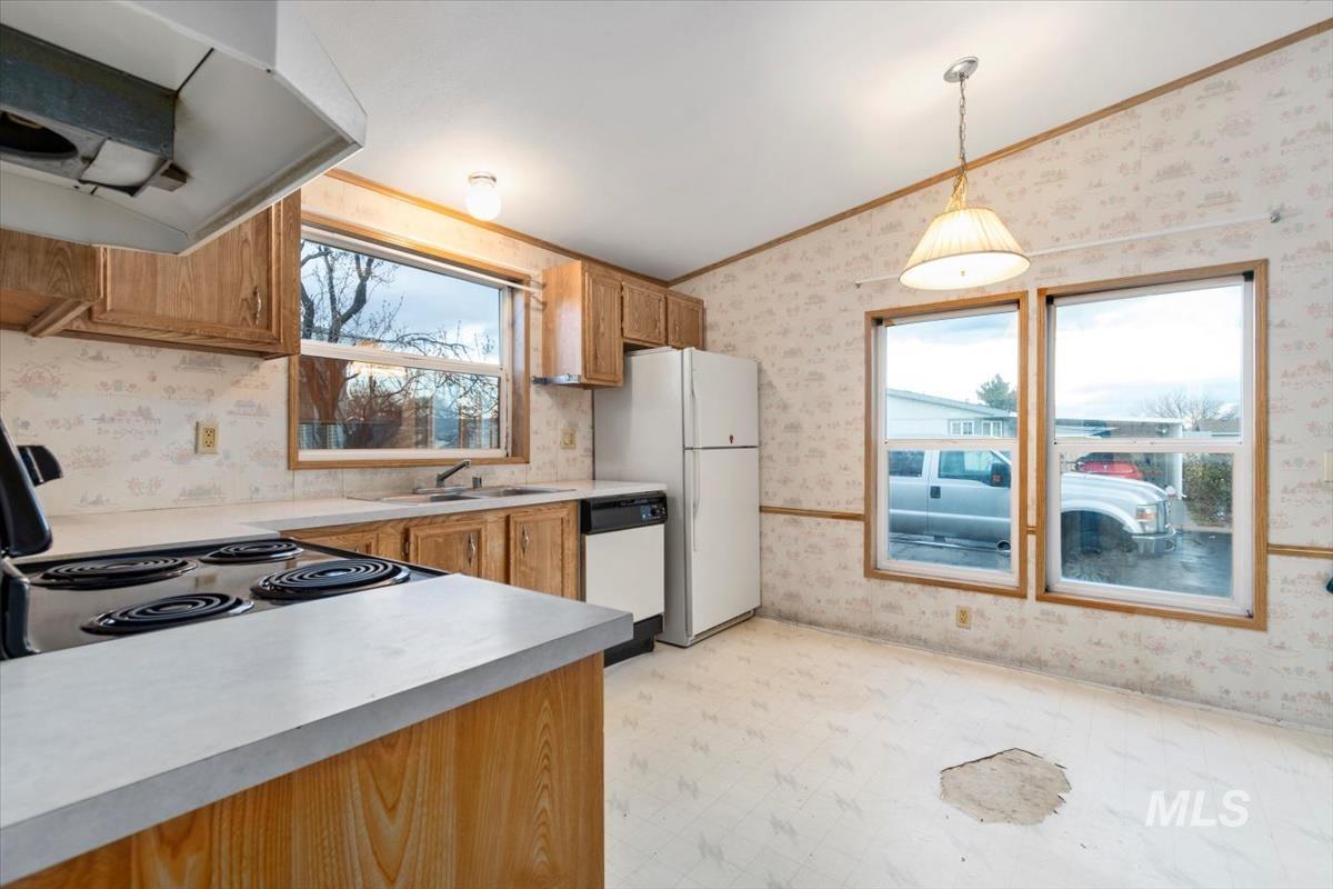 2804 Golden Rod Lane Caldwell, ID 83605 - Photo 23 of 35 Kitchen featuring wallpapered walls, ventilation hood, brown cabinets, light floors, and pendant lighting