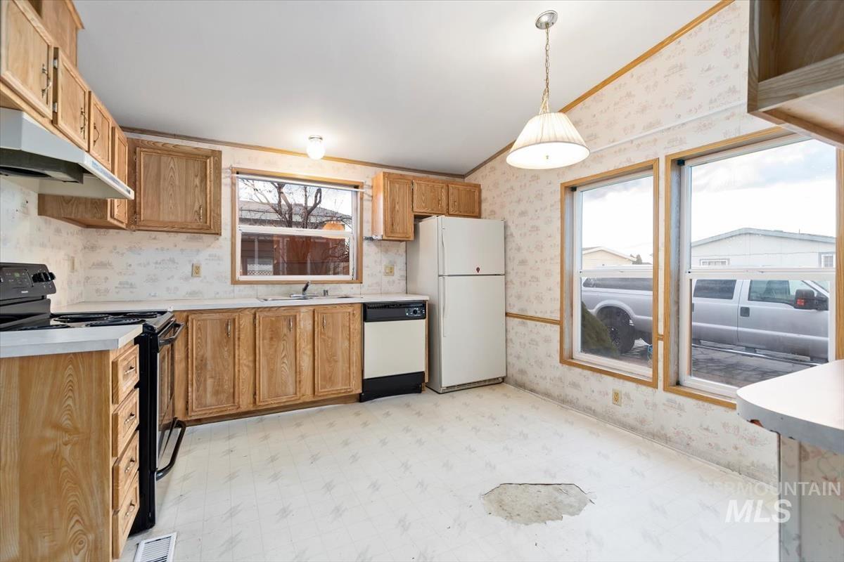 2804 Golden Rod Lane Caldwell, ID 83605 - Photo 24 of 35 Kitchen with wallpapered walls, light floors, black range with electric stovetop, light countertops, and pendant lighting