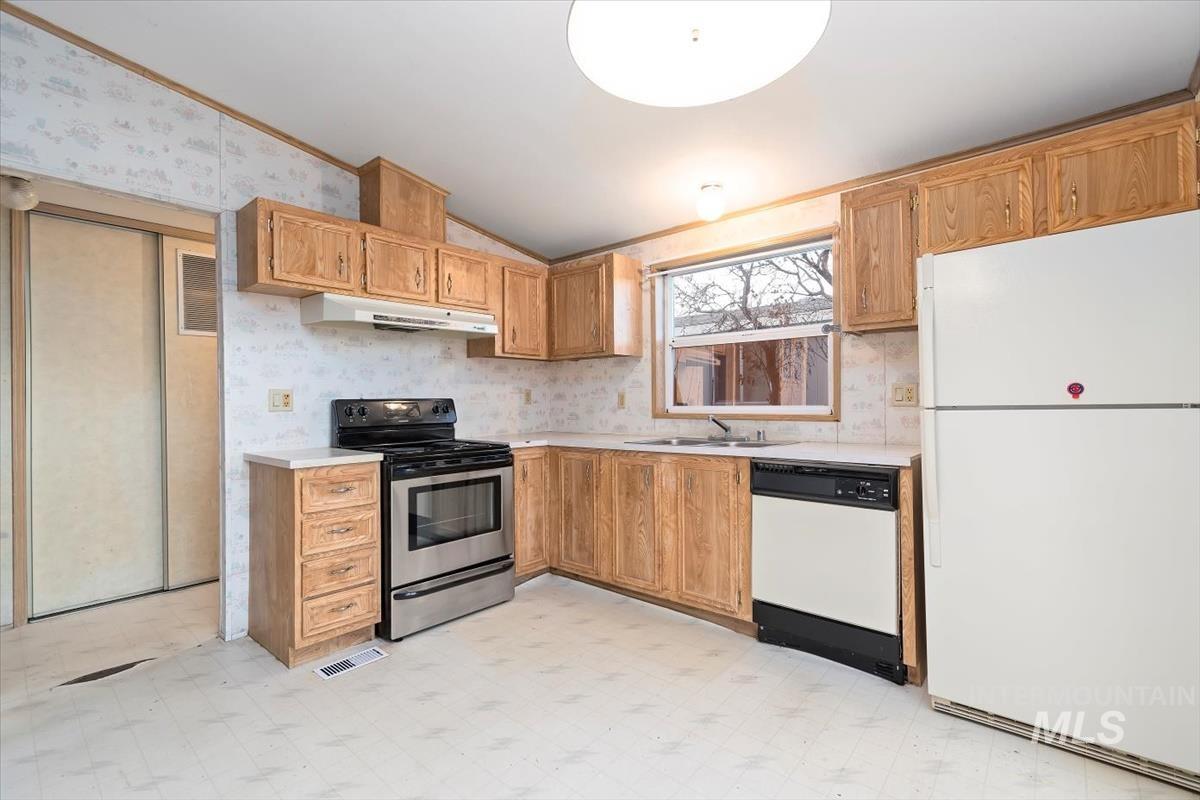 2804 Golden Rod Lane Caldwell, ID 83605 - Photo 26 of 35 Kitchen with light flooring, white appliances, lofted ceiling, light countertops, and wallpapered walls