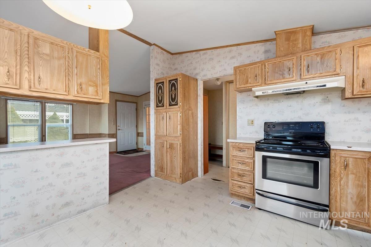 2804 Golden Rod Lane Caldwell, ID 83605 - Photo 28 of 35 Kitchen with electric stove, light countertops, wallpapered walls, light floors, and under cabinet range hood