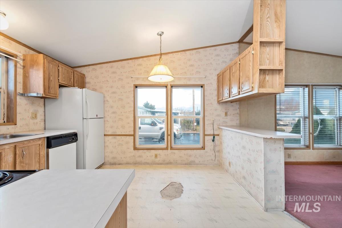 2804 Golden Rod Lane Caldwell, ID 83605 - Photo 30 of 35 Kitchen with vaulted ceiling, light countertops, wallpapered walls, dishwasher, and decorative light fixtures