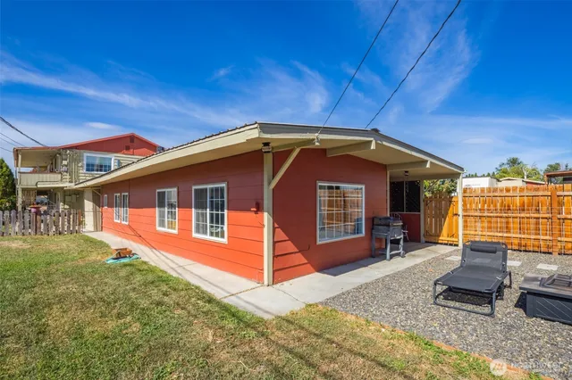 a view of a house with a yard porch and wooden fence