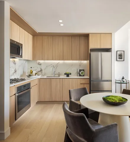 a kitchen with stainless steel appliances granite countertop a sink a stove a refrigerator cabinets and a dining table with wooden floor