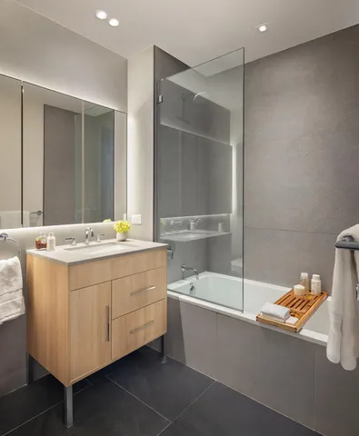 a bathroom with a double vanity sink mirror and bathtub
