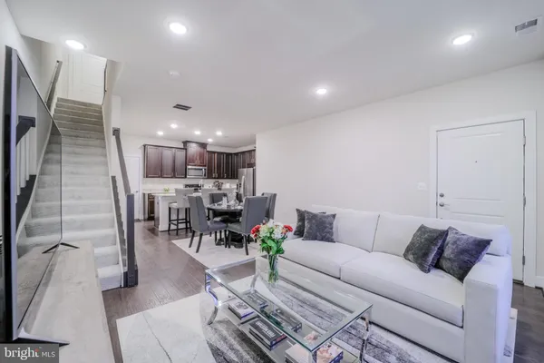 a living room with furniture a kitchen view and a wooden floor