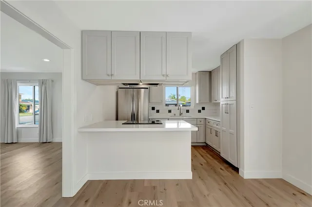 a kitchen with stainless steel appliances a sink a refrigerator and white cabinets