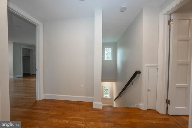 a view of staircase with wooden floor and white walls
