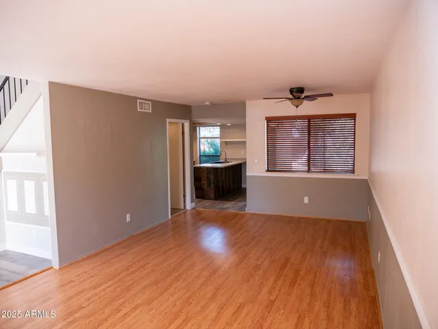 a view of a livingroom with wooden floor and kitchen