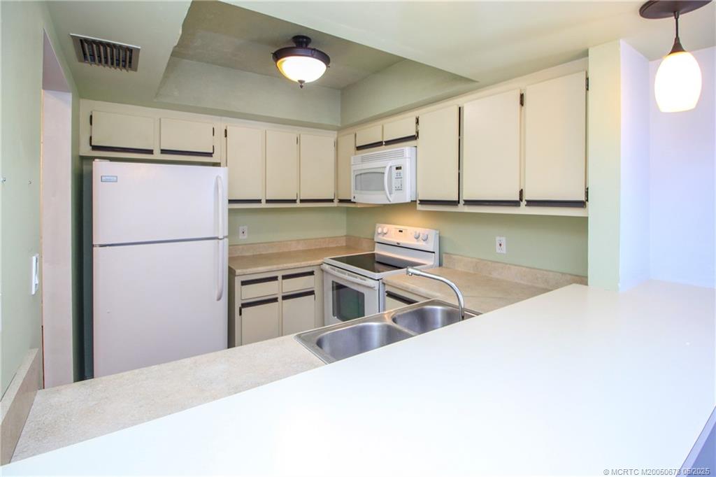 801 Southeast Central Parkway, Unit 8019 Stuart, FL 34994 - Photo 18 of 41 a kitchen with stainless steel appliances granite countertop a refrigerator sink and white cabinets