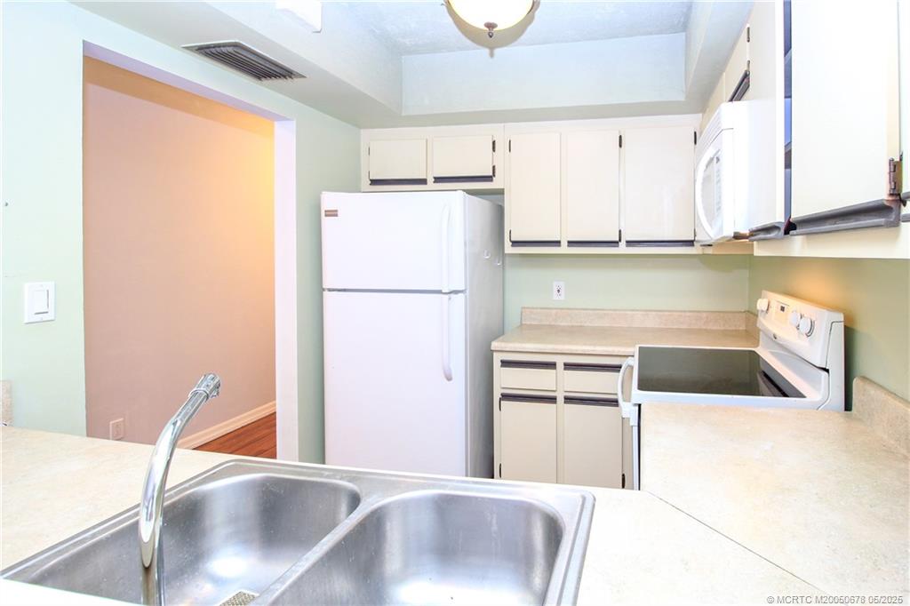 801 Southeast Central Parkway, Unit 8019 Stuart, FL 34994 - Photo 19 of 41 a kitchen with a refrigerator sink and white cabinets