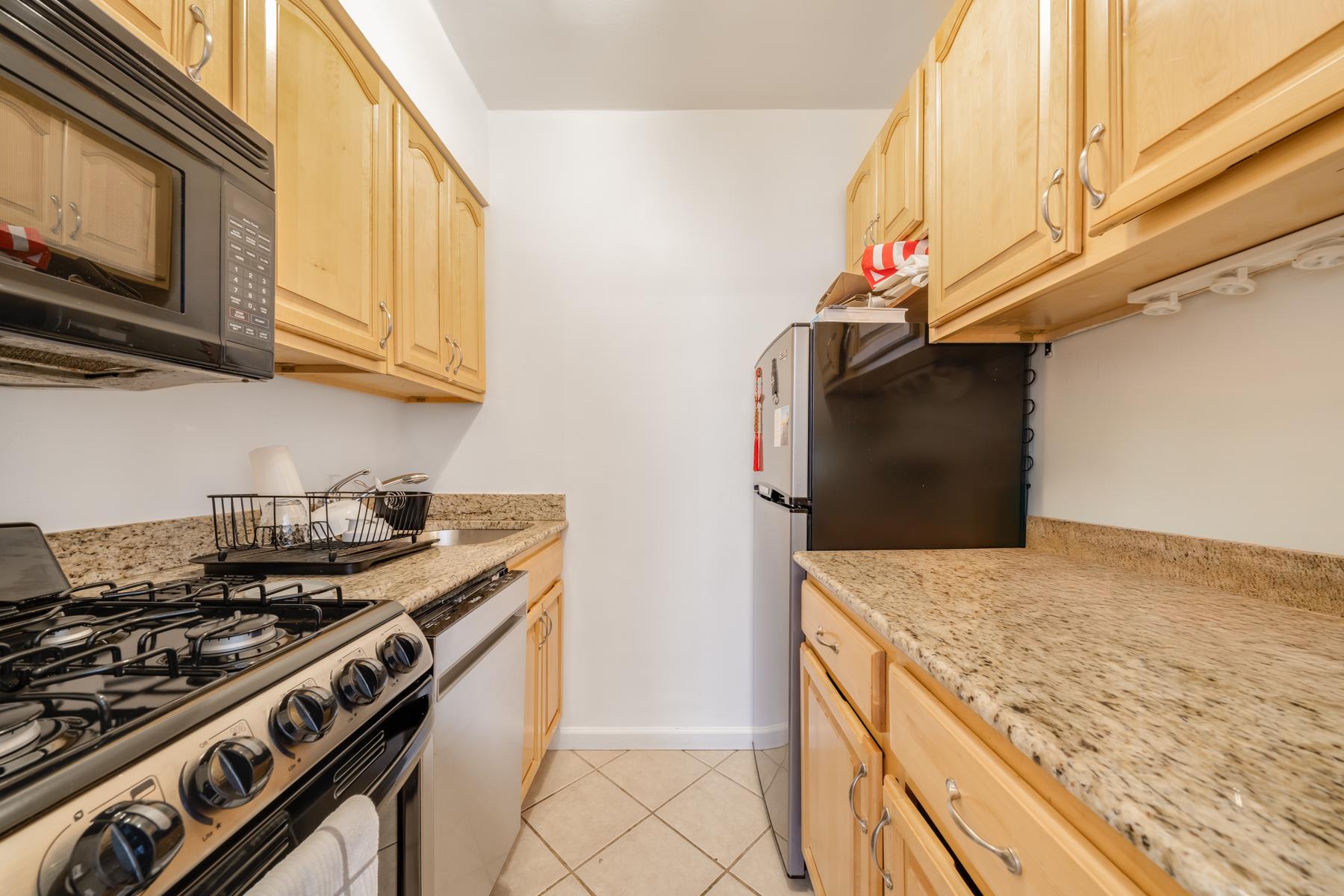 50-54 East 8th Street, Unit 6L Manhattan, NY 10003 - Photo 6 of 10 a kitchen with stainless steel appliances granite countertop a stove and a microwave