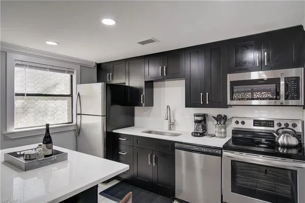 a kitchen with kitchen island granite countertop a sink stainless steel appliances and cabinets