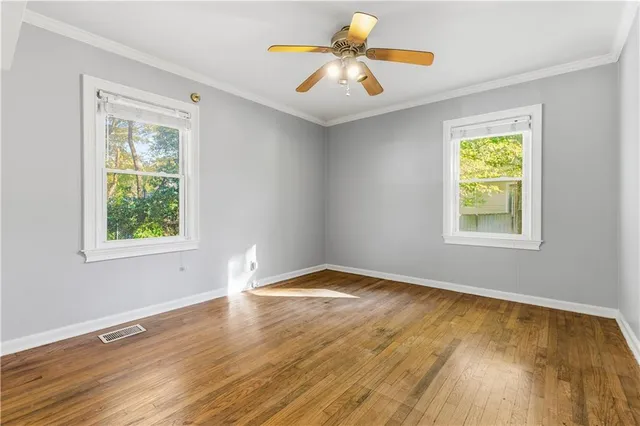 a view of an empty room with window and wooden floor