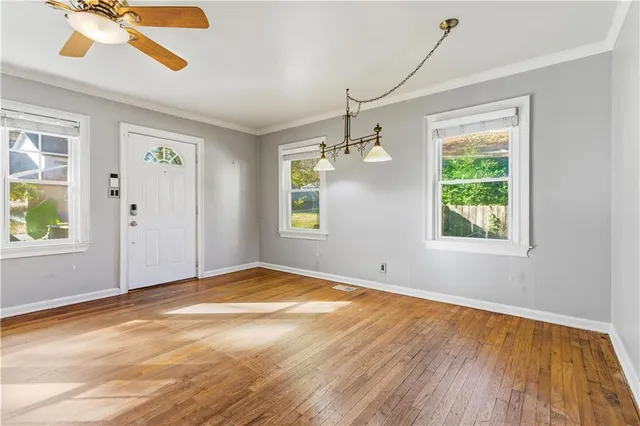 a view of an empty room with window wooden floor and a kitchen view
