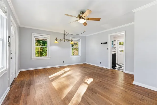 a view of an empty room with wooden floor and a window