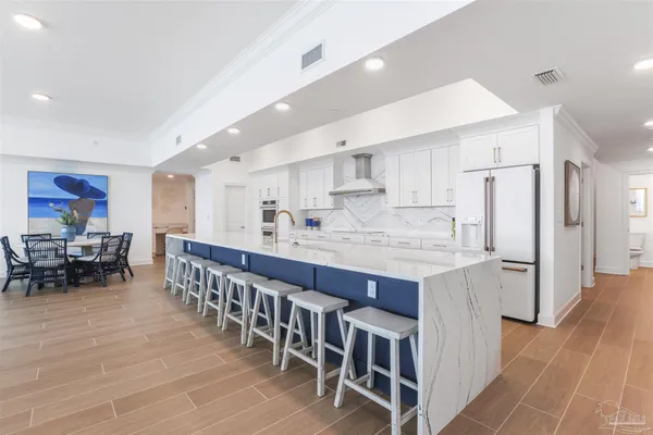 a large white kitchen with stainless steel appliances granite countertop lots of white cabinets a sink and dishwasher