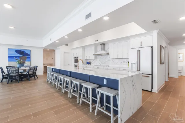 a large white kitchen with stainless steel appliances granite countertop lots of white cabinets a sink and dishwasher