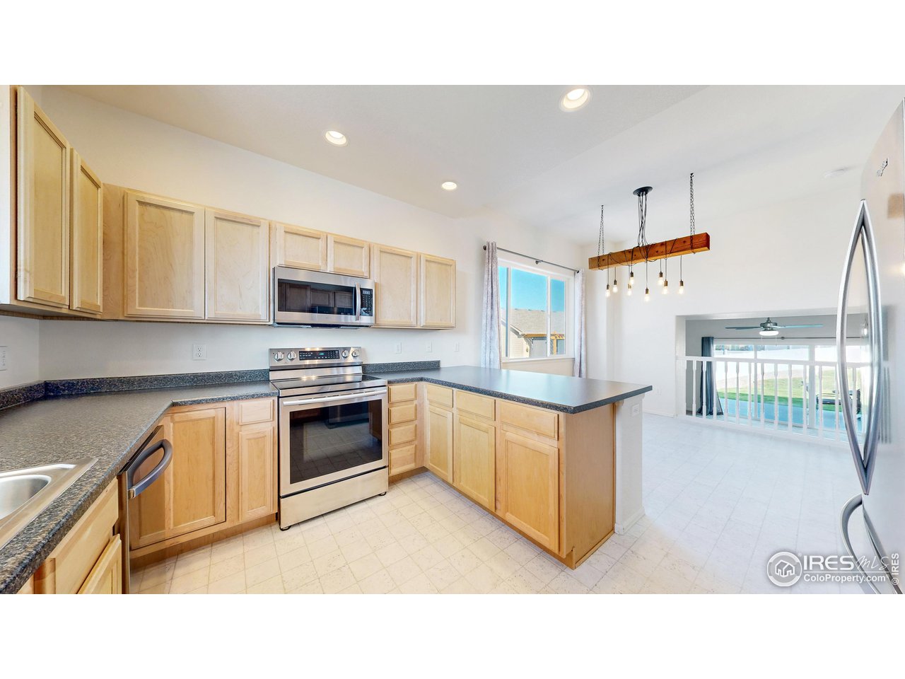 684 Takin Drive Severance, CO 80550 - Photo 8 of 38 a kitchen with stainless steel appliances kitchen island granite countertop a stove a sink and a microwave