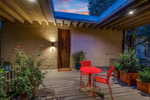 a backyard of a house with table and chairs with potted plants