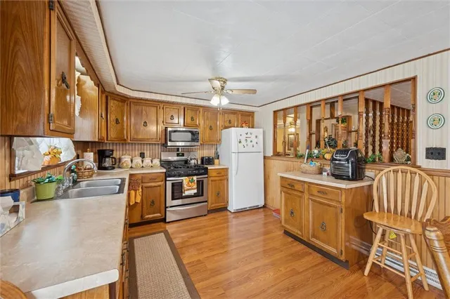 a kitchen with stainless steel appliances granite countertop a stove top oven a sink dishwasher a dining table and chairs with wooden floor