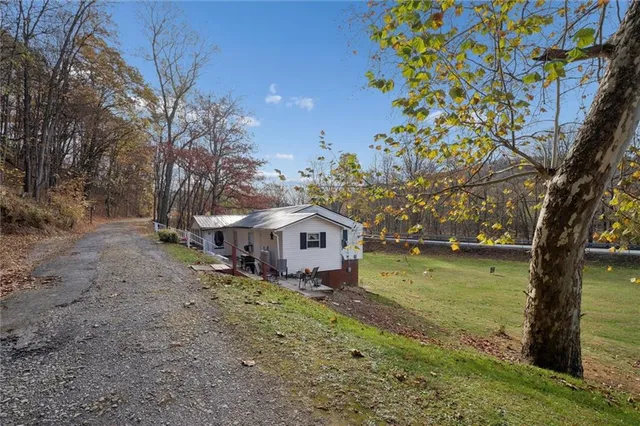 a front view of a house with a yard and large trees