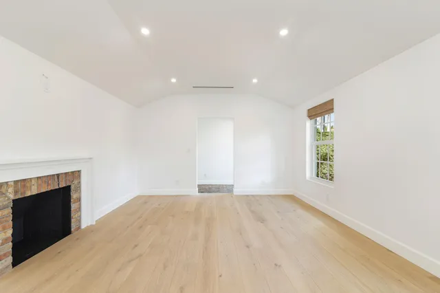an empty room with windows and fireplace