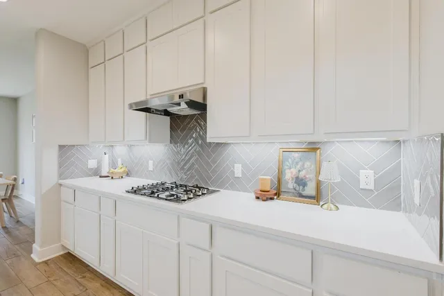 a kitchen with stainless steel appliances granite countertop a sink a stove and white cabinets