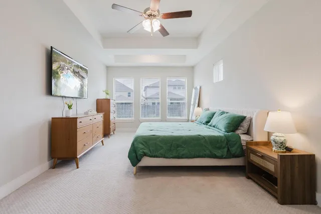 a spacious bedroom with a bed and a flat tv screen on dresser